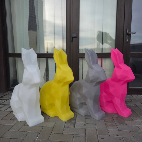 Four colorful rabbit-shaped sculptures in front of a glass door.