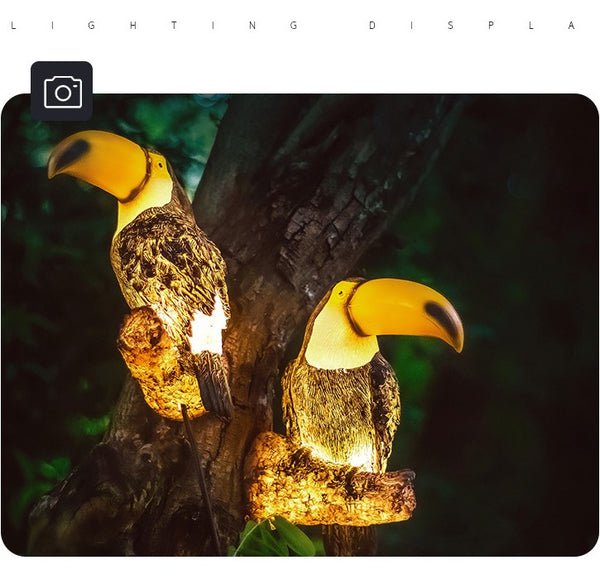 Two illuminated toucan statues on a dark background