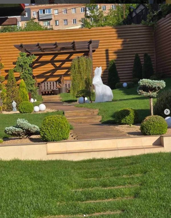 Garden with wooden pergola, decorative elements, and a building in the background