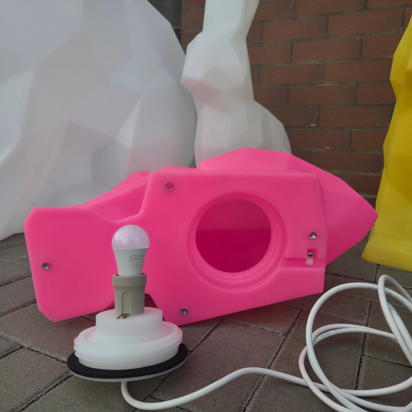 Pink and white device with a light bulb on a brick surface