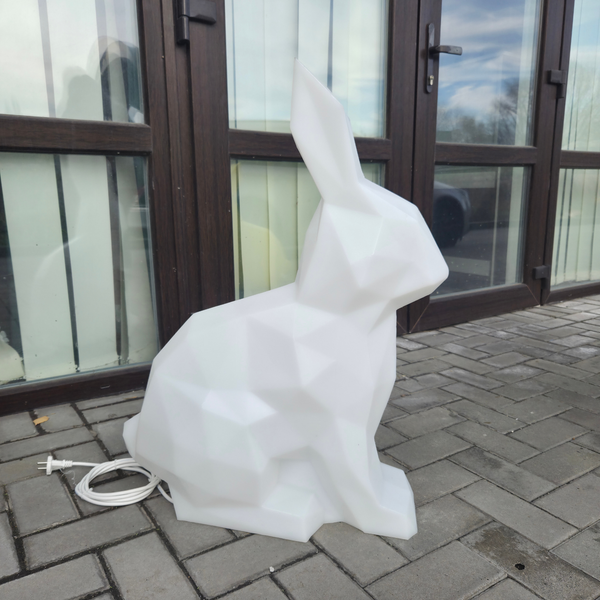 White rabbit-shaped lamp on a patio with glass doors in the background