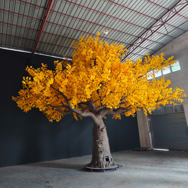 Large artificial tree with yellow leaves in a warehouse setting
