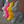 Four geometric rabbit sculptures in different colors (gray, pink, yellow, white) against a brick wall.