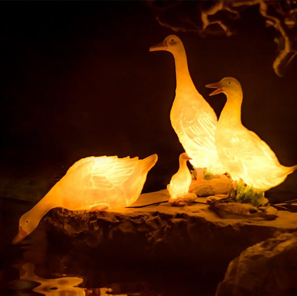Three illuminated goose-shaped lamps on a dark background