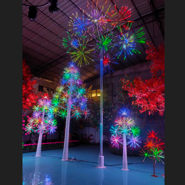 Colorful LED firework tree light fixtures displayed in a large indoor event space, with multiple trees glowing with red, green, blue, and purple lights.
