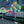 Outdoor LED firework-shaped light trees decorated with bright cyan, yellow, white, and pink lights, set along a sidewalk in front of a building at night.