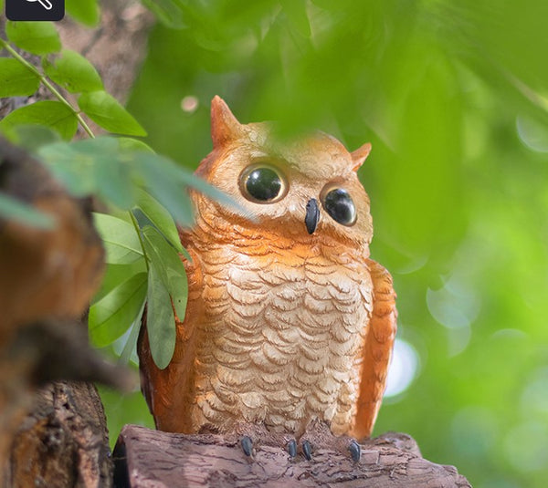Owl perched on a branch with a blurred green background