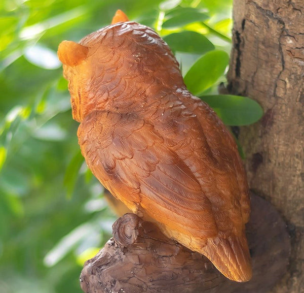 Close-up detail of owl garden statue feathers and branch texture