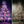 A split-screen view of a copper-finished metal starburst Christmas tree. The left side shows the tree lit with multicolor LED starburst lights against a dark purple background, while the right side shows the bare copper metal frame of the tree against a dark gray background.