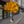 An artificial ginkgo tree with bright yellow leaves and a brown trunk, planted on a paved sidewalk in front of a modern building. Two small white rabbit decorations and two small solar panels are placed at the base of the tree.